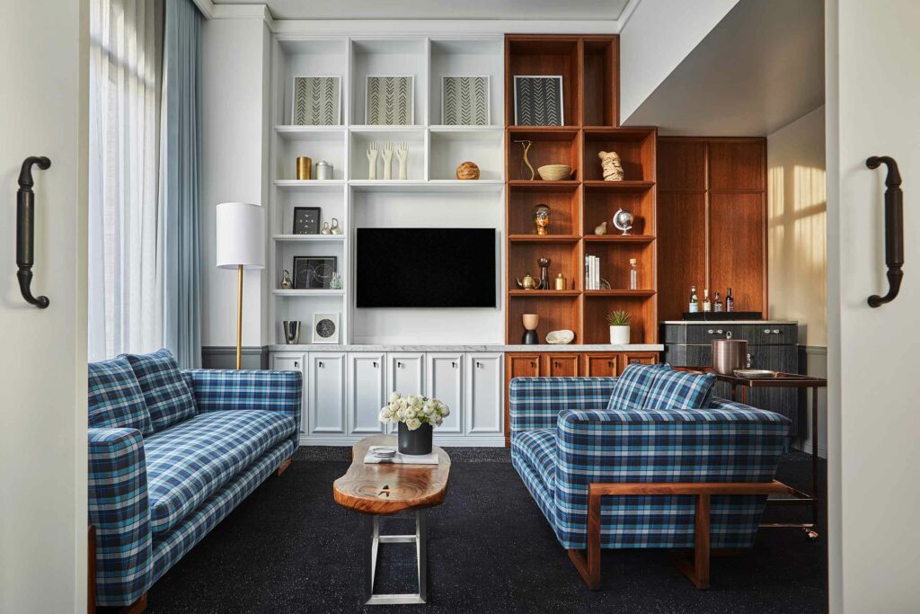 A lounge space with blue checkered sofas and wooden shelves.