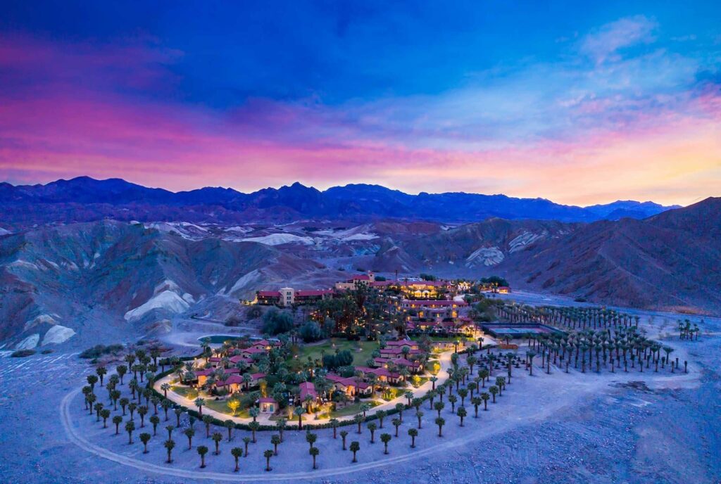 Exterior birds-eye view of The Oasis at Death Valley against a desert backdrop at twilight. 