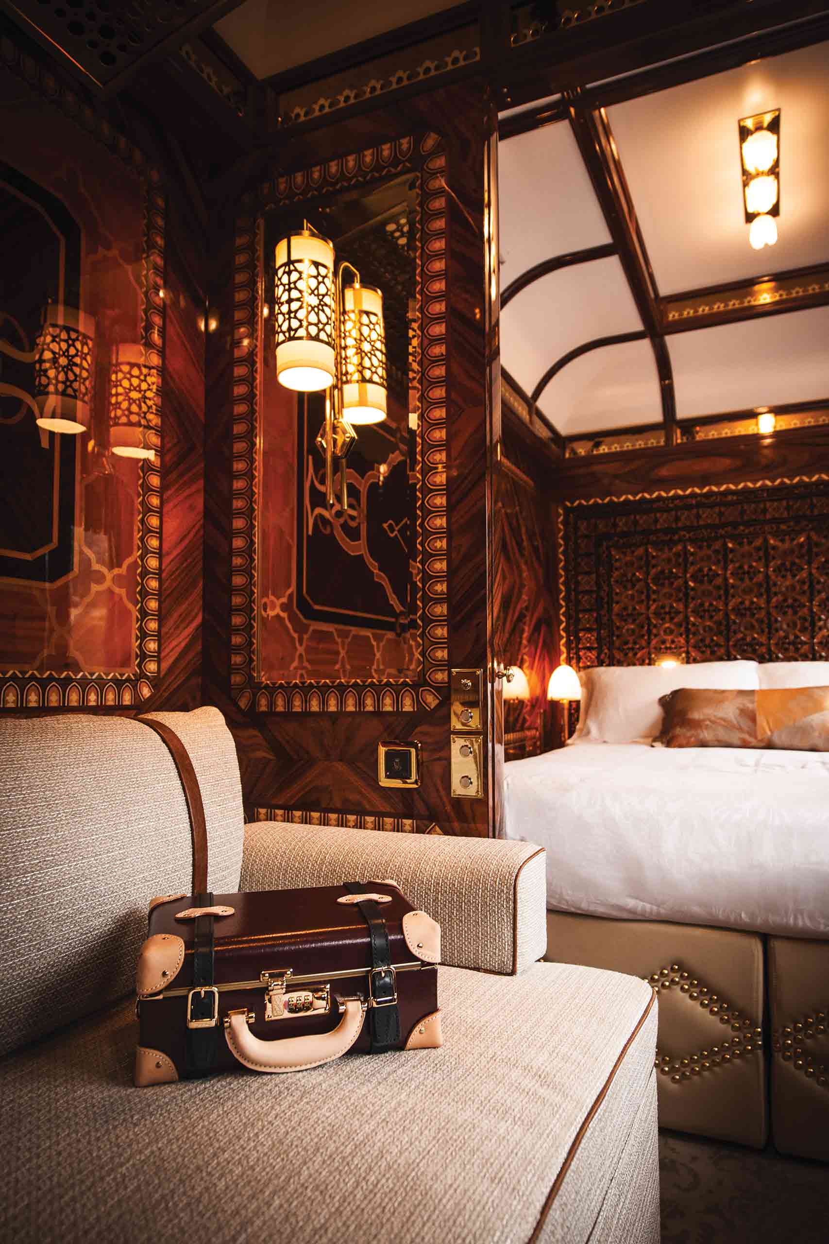 A old-fashioned suitcase in the train cabin with a double bed in the background.