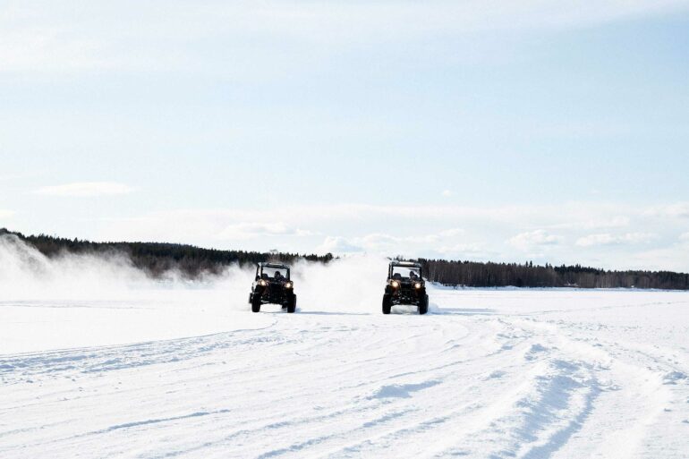 Two vehicles drive in the snow in the Arctic Circle, Finland