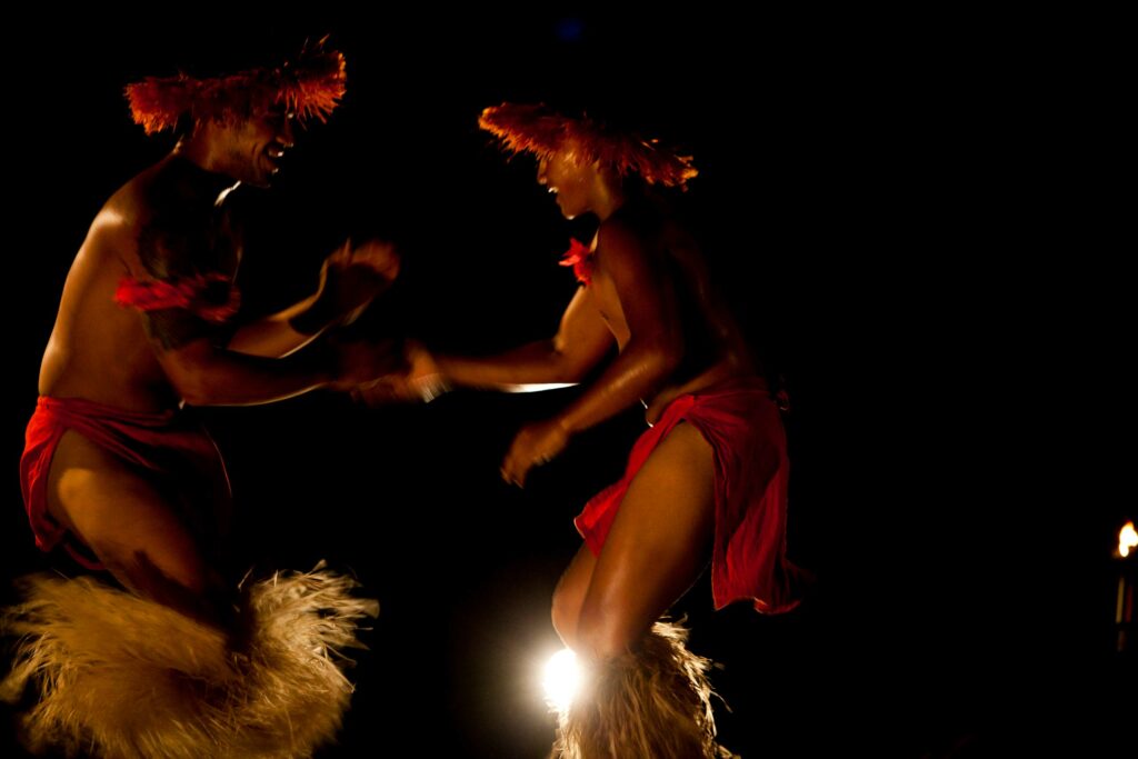 A man and woman engaging in a traditional Polynesian dance. 