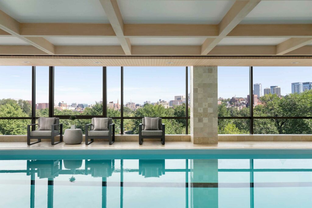 An indoor pool brightly lit by large floor-to-ceiling windows.