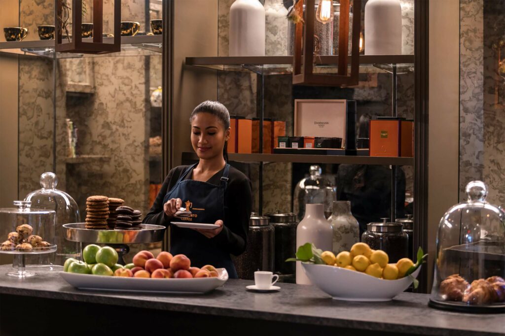 A barista at the Four Seasons Boston preparing fresh juices and sweet snacks for guests. 