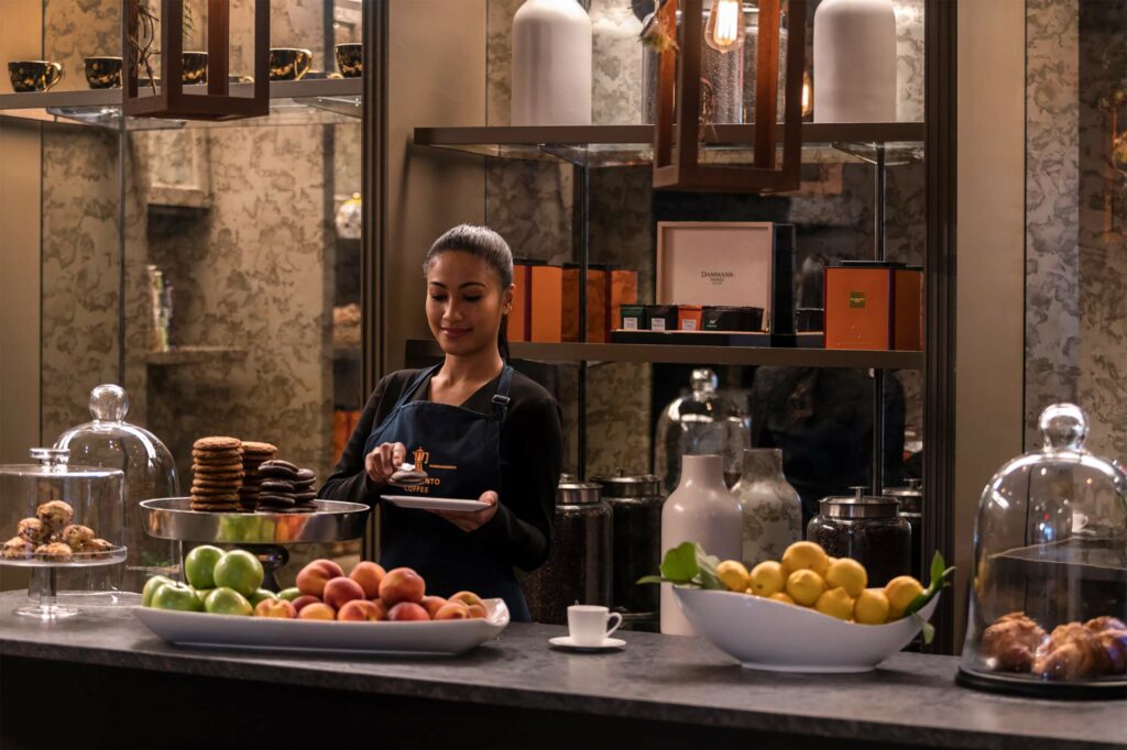 A barista at the Four Seasons Boston preparing fresh juices and sweet snacks for guests.