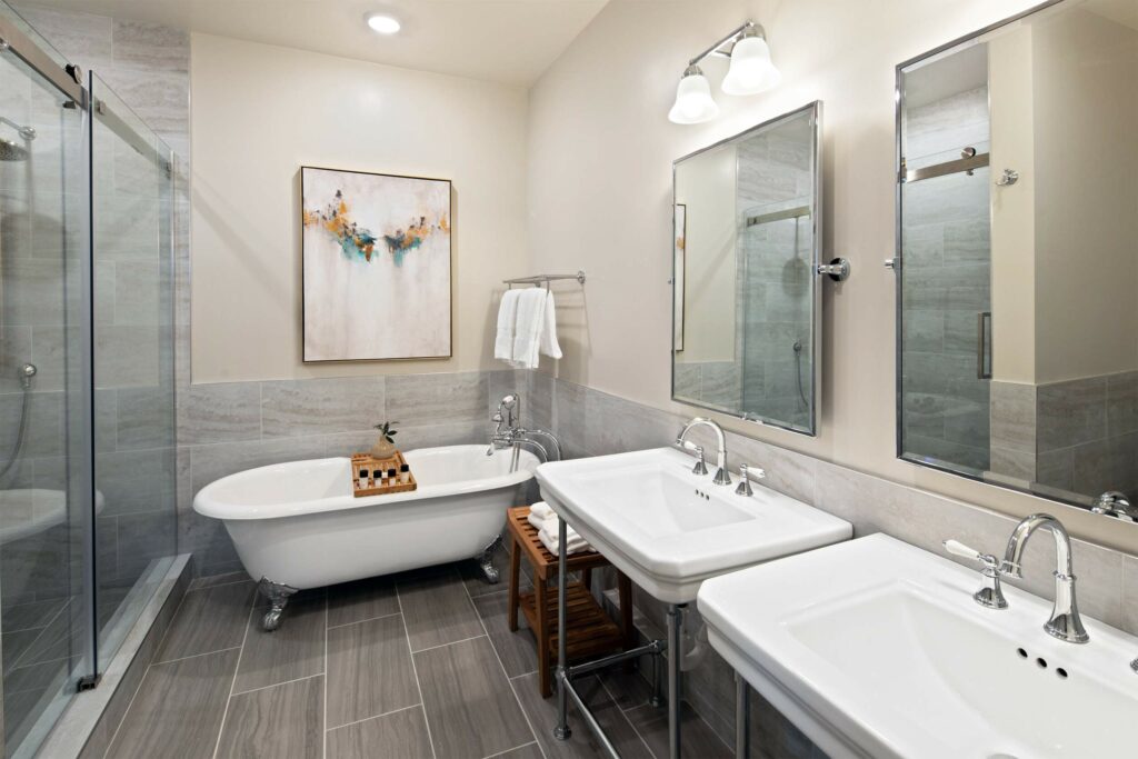 A quant bathroom with two basins, a freestanding bathtub, and grey tiles.