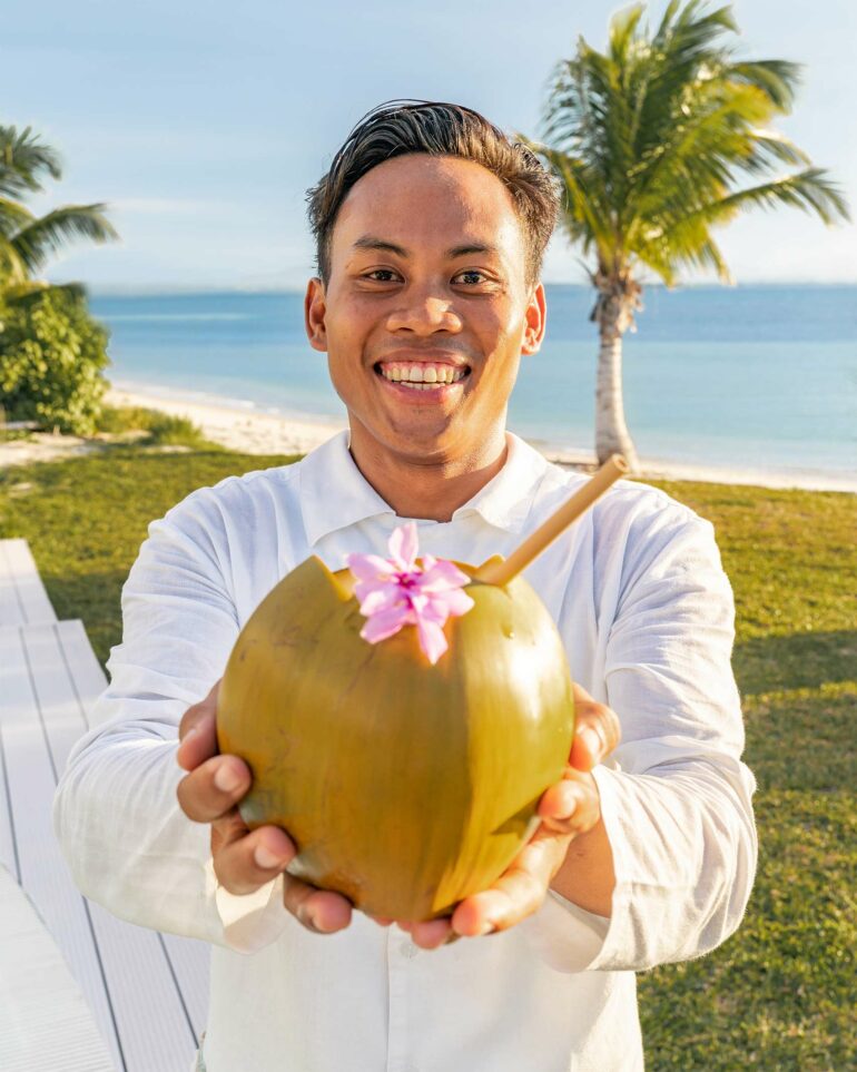 A staff members holds up a coconut as a welcome to Miavana by Time + Tide, Nosy Ankao, Madagascar