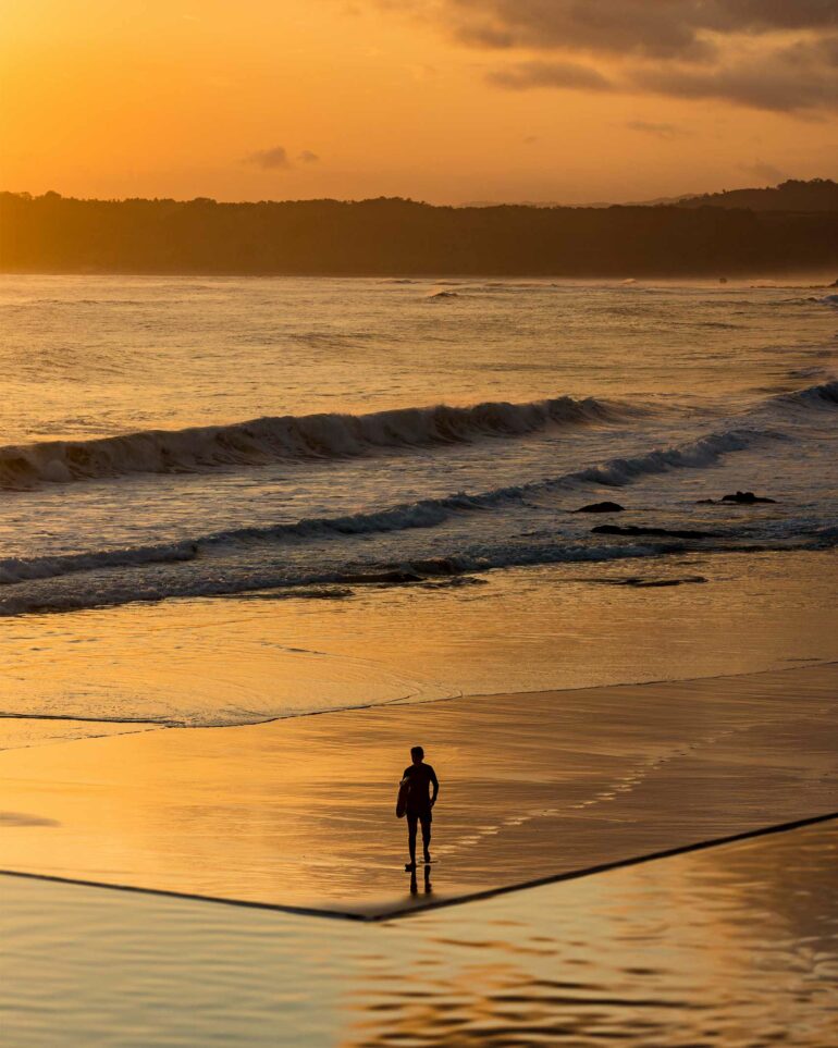 A guest stands on the beach at sunset, NIHI Sumba, Sumba, Indonesia