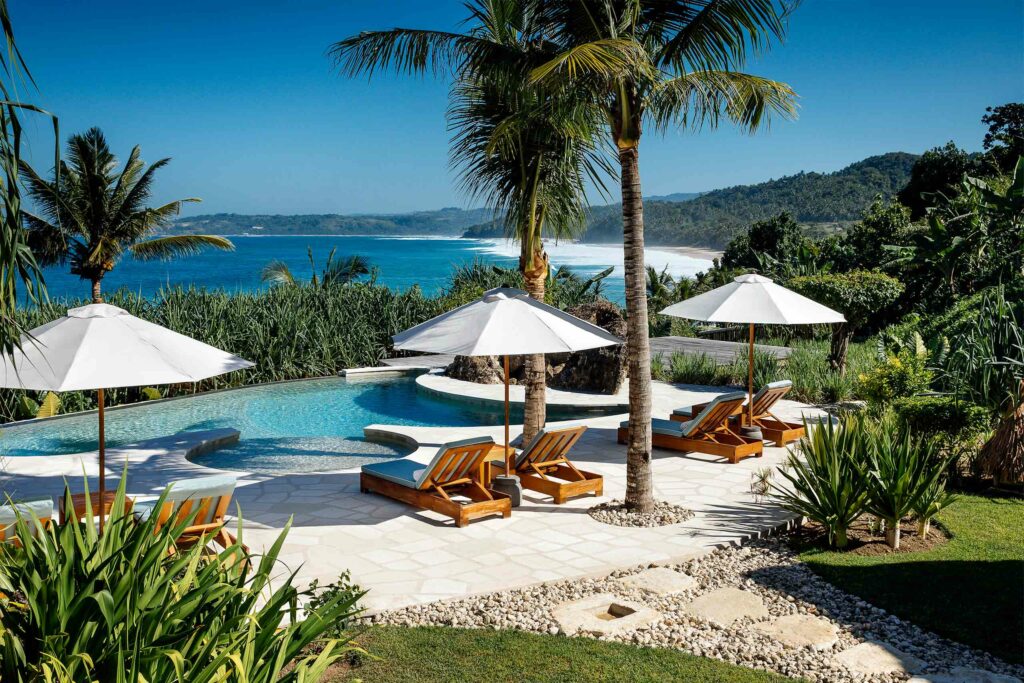 White parasols by a pool at NIHI Sumba, Sumba, Indonesia