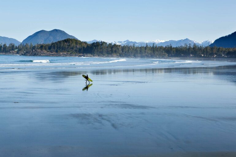A surfer walks towards the shore in Tofino, Vancouver Island, Canada