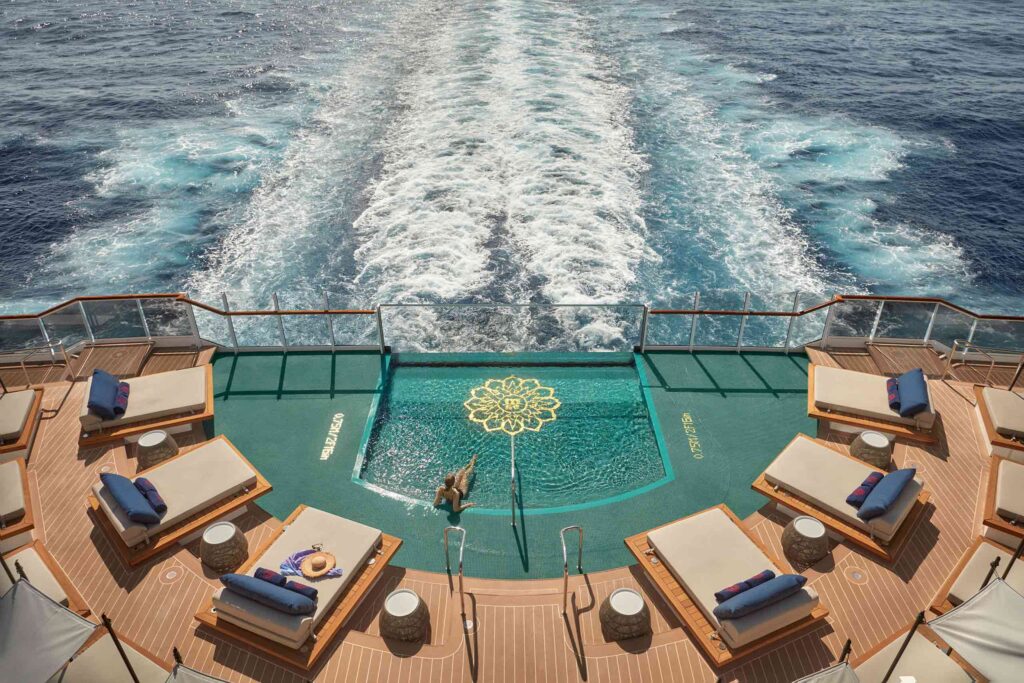 A woman relaxes in the aft pool of EXPLORA I looking out to sea