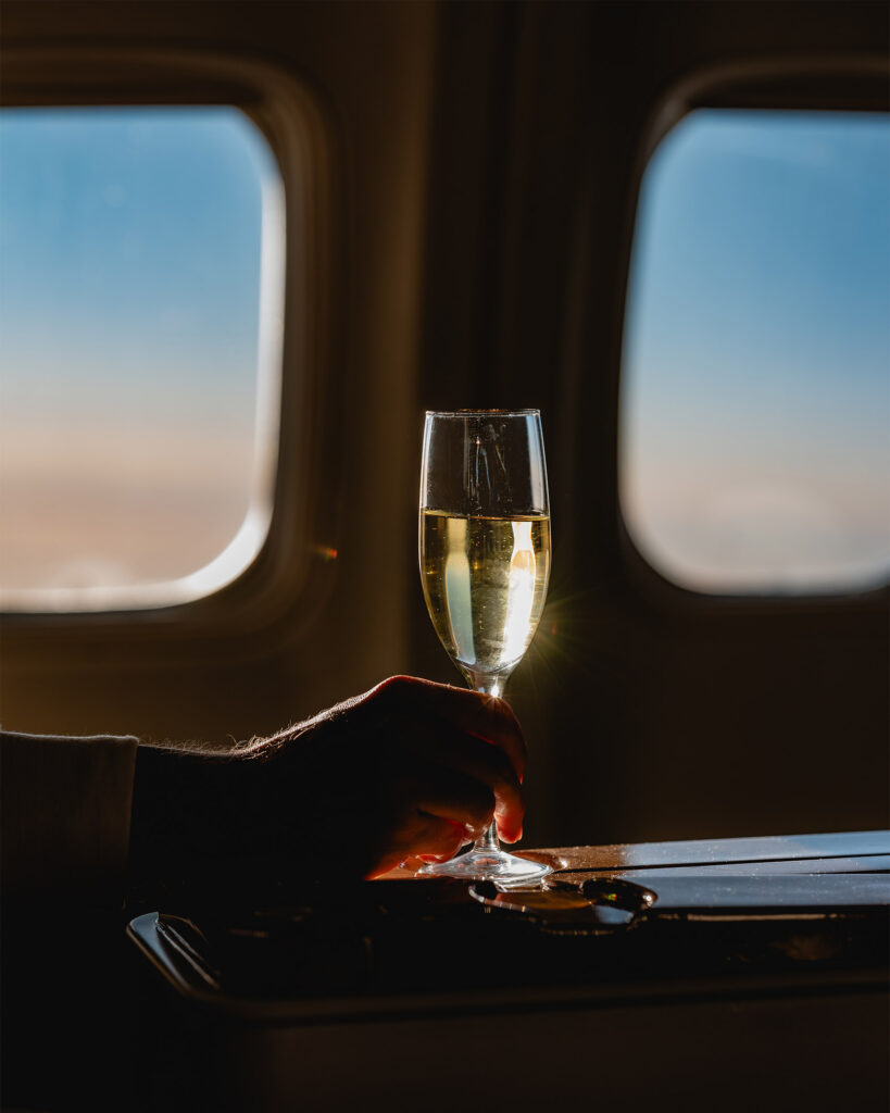 A glass of champagne held by a passenger travelling with Abercrombie & Kent Private Jet Journeys.