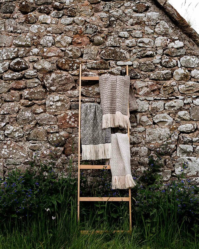 Signature feather scarves by Araminta Campbell displayed on a ladder in Edinburgh, Scotland