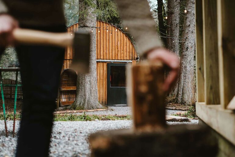 A man chops wood in a forest. Scottish hotels are all about nature experiences