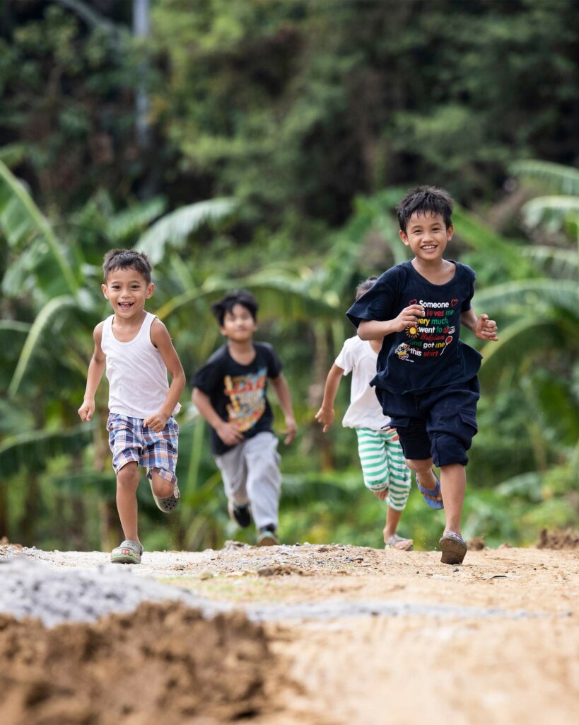 Children run through a rural landscape. 