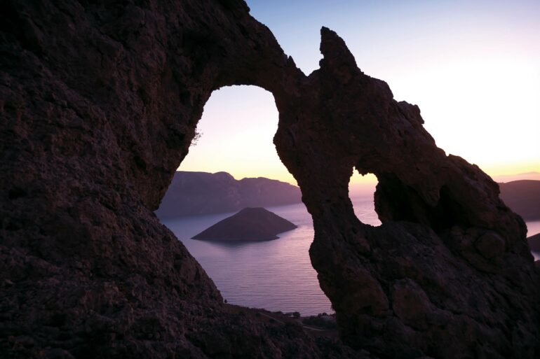 The sun sets over a dramatic rock formation on Kalymnos, Greece
