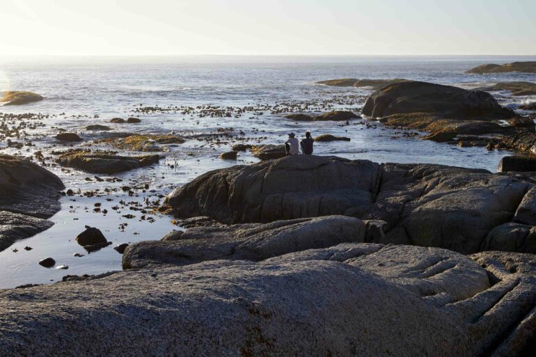 Two people sit on a rock looking out over the sea in Camps Bay, Postcards from Cape Town, Cape Town, South Africa