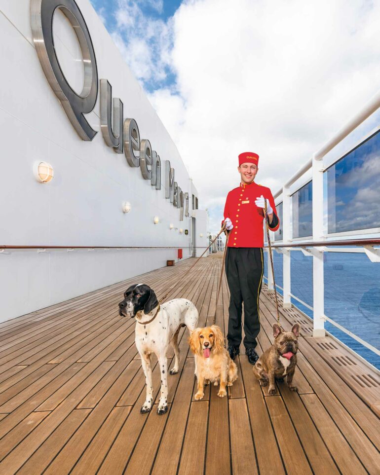 A staff member walks dogs aboard the Queen Mary 2, Cunard