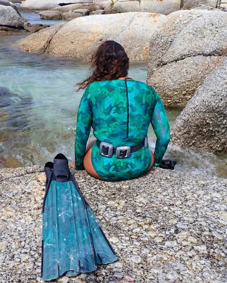A snorkeler sits on a rock by the shore in Cape Town, South Africa