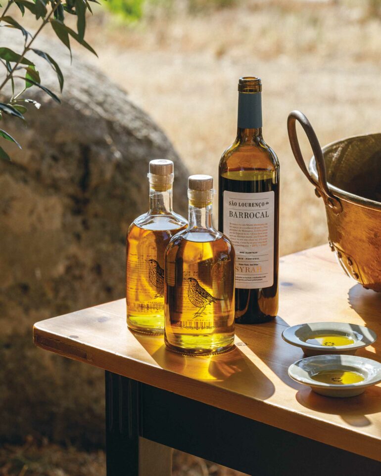 A bottle of wine and two bottles of olive oil stand on a table at São Lourenço do Barrocal, Alentejo, Portugal