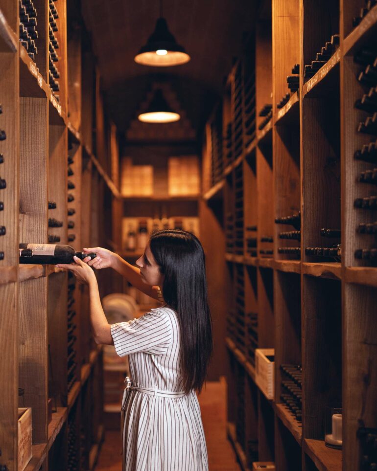 A sommelier chooses a bottle of wine from the wine cellar at Villa Ardore, Tuscany, Italy
