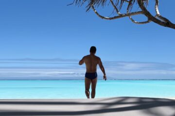Man walking out to sea in French Polynesia to a turquoise sea