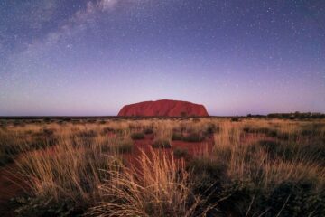 Uluru or Ayers Rock, is a massive sandstone monolith located in the Northern Territory's "Red Centre" of Australia, set to a star studded sky
