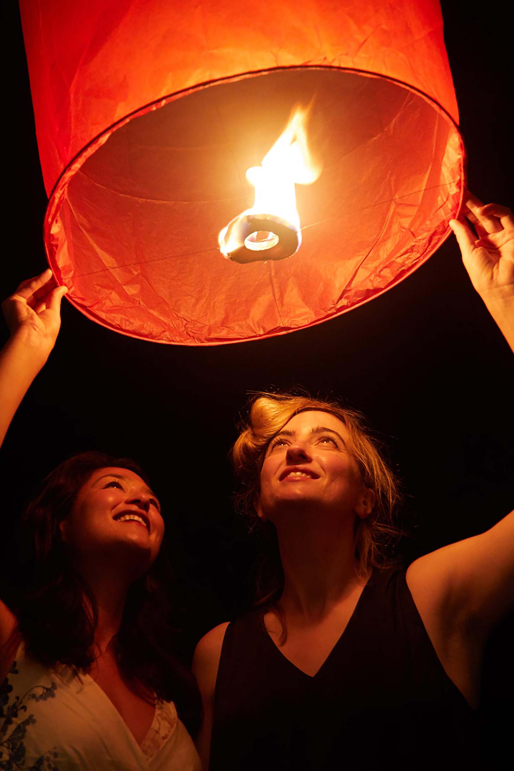 Female couple lighting a lantern in Thailand