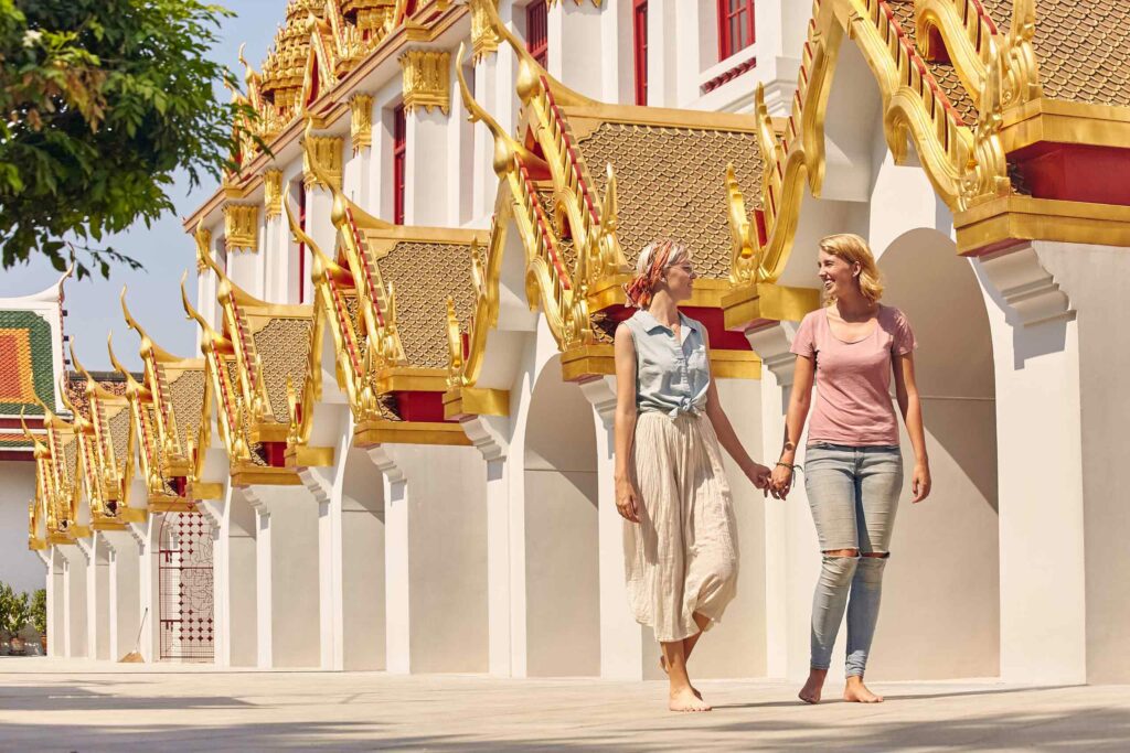A lesbian couple explores the temples of Bangkok. Thailand is one of the most exciting destinations for same-sex weddings in 2024