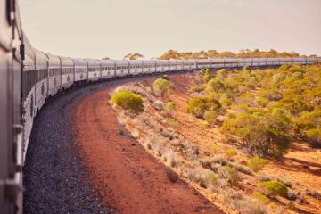 Australia's long, silver Indian Pacific railway train carraiges curve its way on a journey through the outback