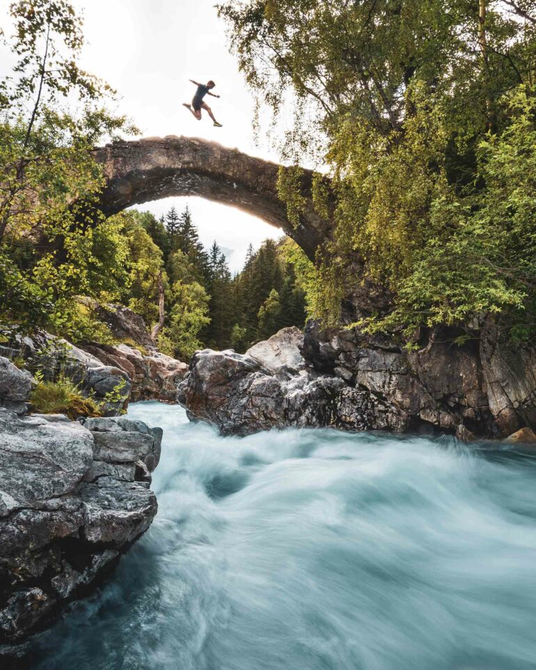 A visitors jumps on a bridge over a stream in Les Deux Alpes, France