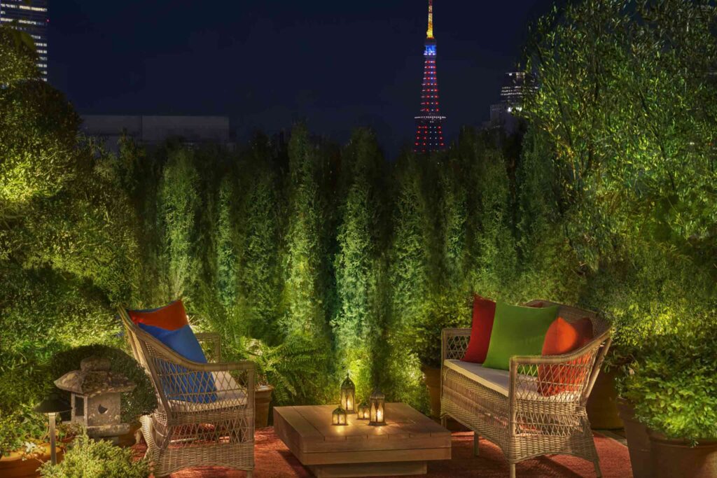 Lush plants flank the roof terrace of Tokyo EDITION Ginza overlooking Tokyo Tower