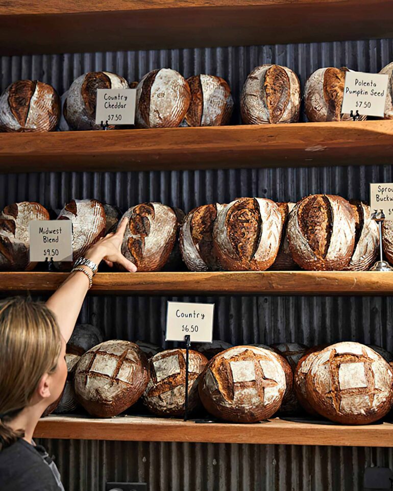 A shop employee points at a loaf of bread at Hewn Bread, Evanston, Illinois, USA