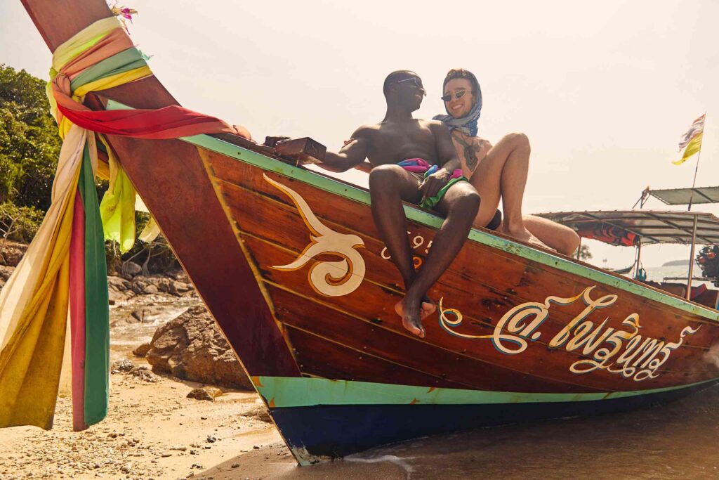 Travel proud in Thailand, gay couple on a traditional Thai fishing boat