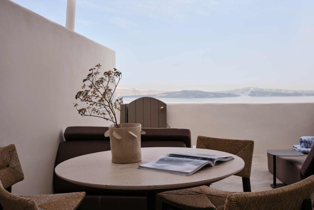 Outside terrace table decorated with a flower pot and dried flowers overlooking the Santorini caldera
