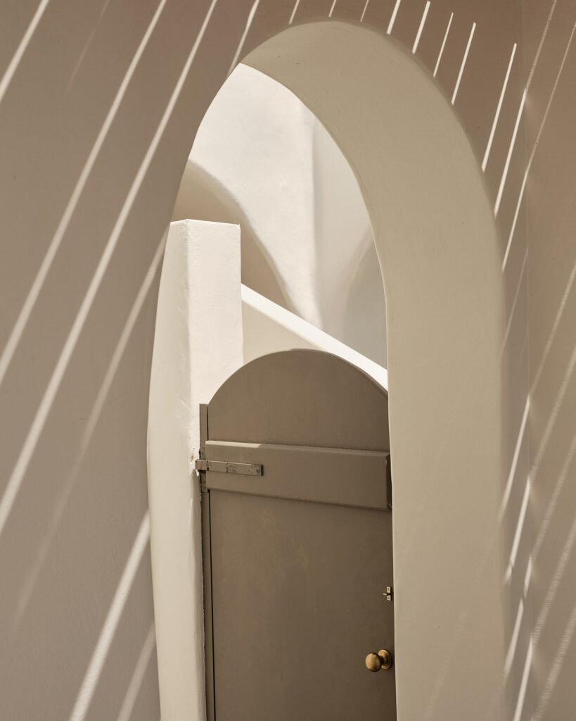 Sun casts its shadows on an ecrue gate at Andronis Boutique Hotel in Santorini