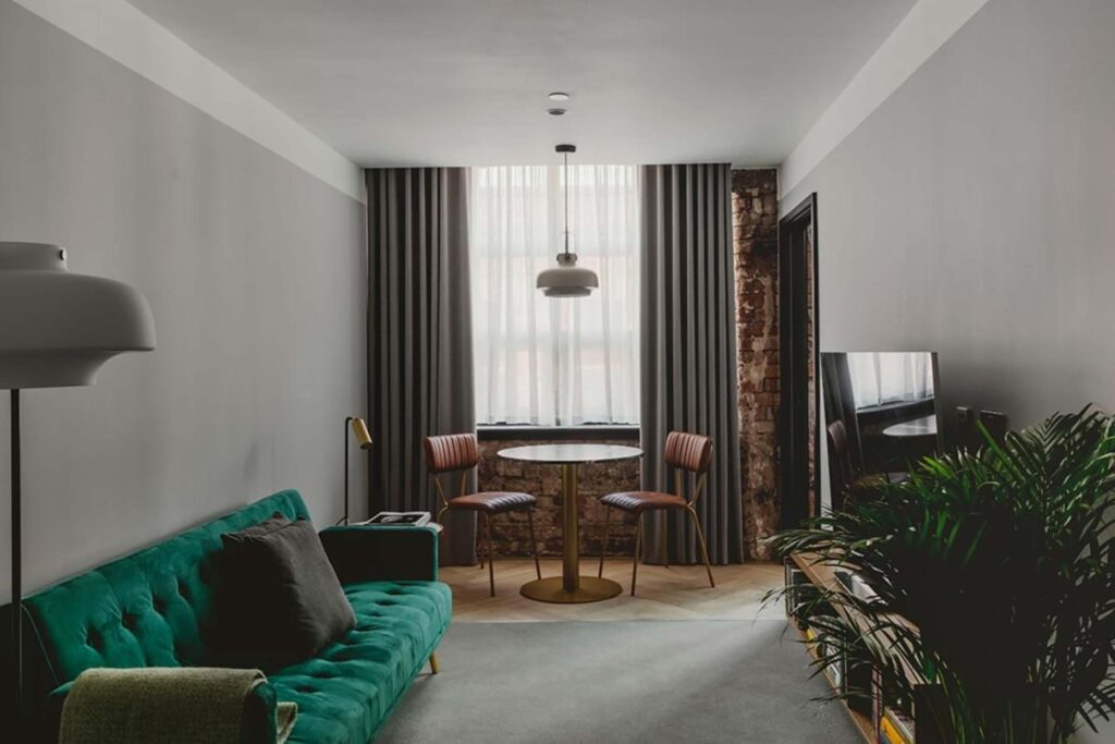 Industrial interiors of room, green velvet sofa, house plants, pendant light and exposed brick at Leven Manchester
