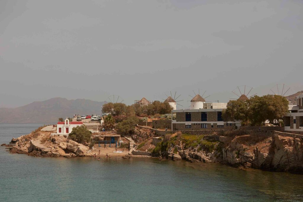 Myconian view of the little town beach, red-roofed church and windmills