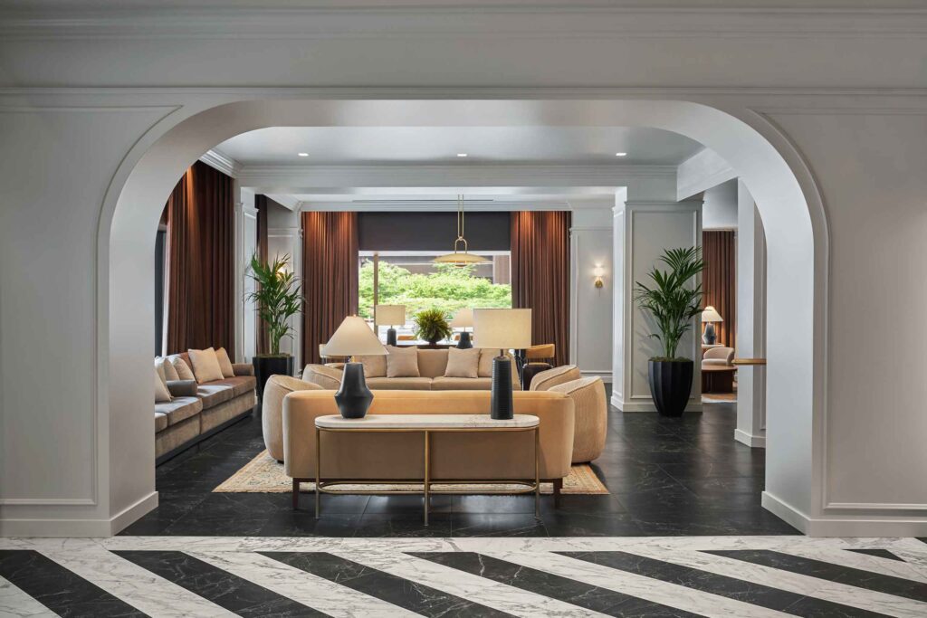 Interiors of reception area, striped marble foreground and conteporary, cleak furnishings in the background as seen through an archway