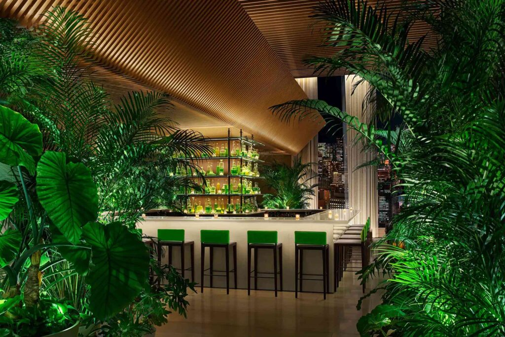 Emerald themed bar with green glass bottles, chairs and foliage
