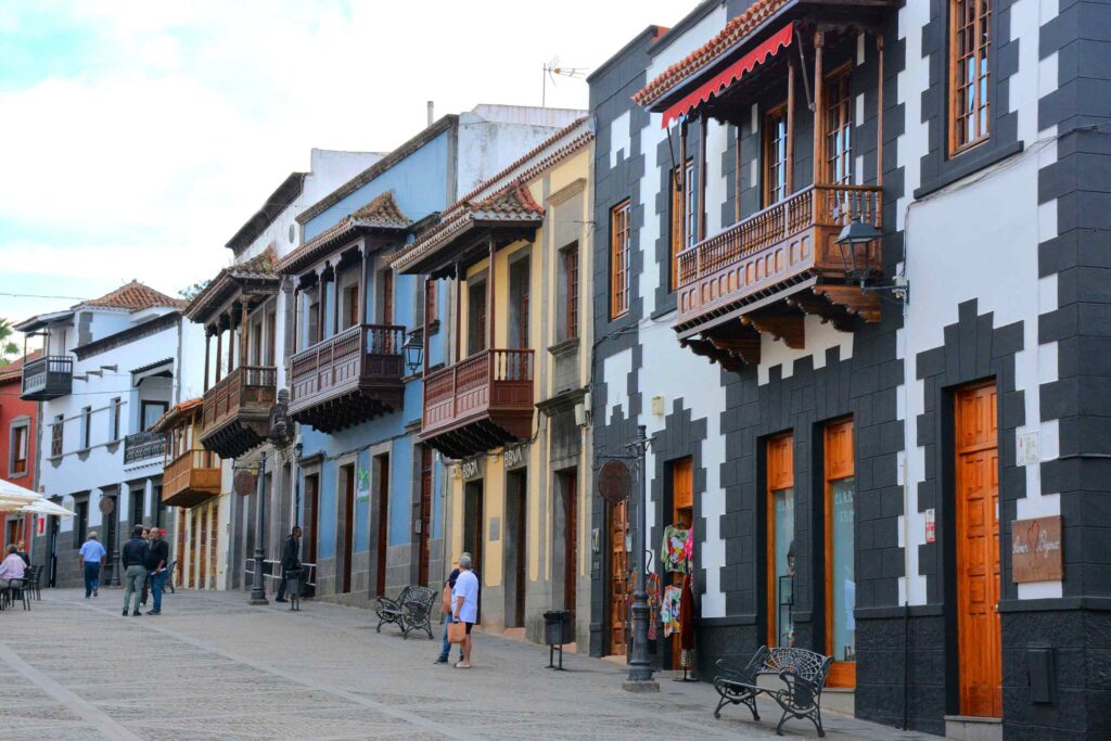 Colourful houses, in monochrome, yellow and blue, with distinctive wooden balconies, flank the street in Teror, Gran Canaria