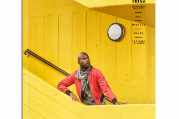 The It's a London Thing Issue of OutThere magazine, featuring a black model with a red jacket and brown and white scarf standing on a bright yellow stairwell