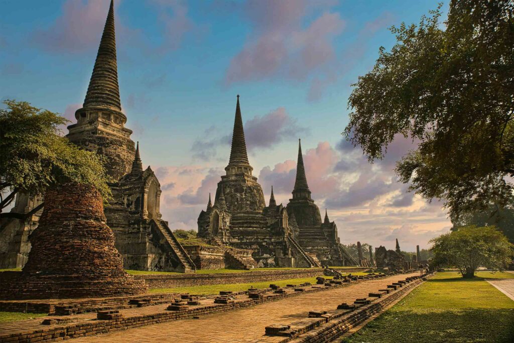 Three ancient structures in Ayutthaya against a blue sky. Ayutthaya is one of the best romantic getaways near Bangkok.