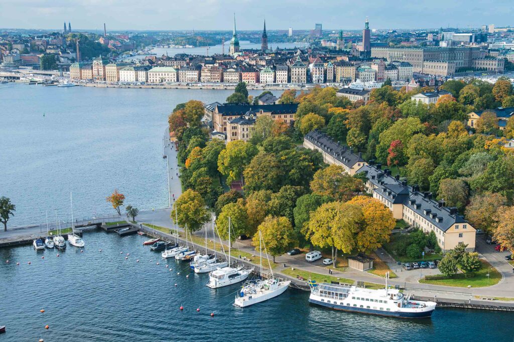 Skeppsholmen Island aerial shot showing it surrounded by waterways. The is green and has a quaint building at its centre.