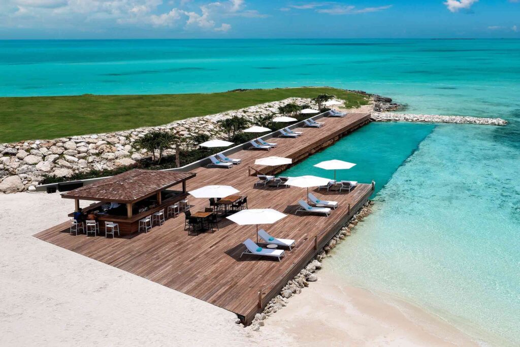 Sea pool in Turks and Caicos. A little beach bar sits on wooded decking. The pool here merges seamlessly into the turquoise sea