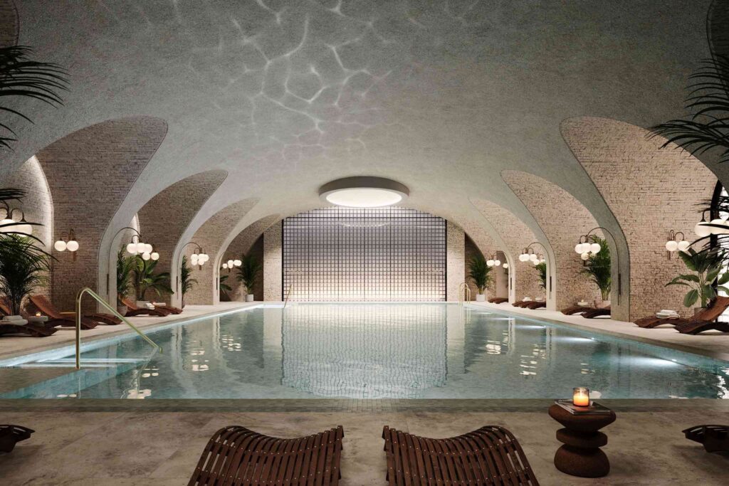 Rendering of the pool area at the Six Senses London, with cavernous subterranean pool, flanked by tiled arches with wooden loungers and lighting