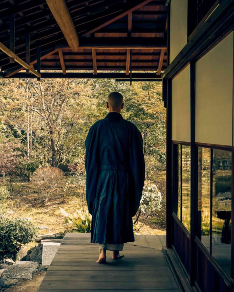 Japanese Buddhist Monk walks through a zen garden and terrace in Kyoto