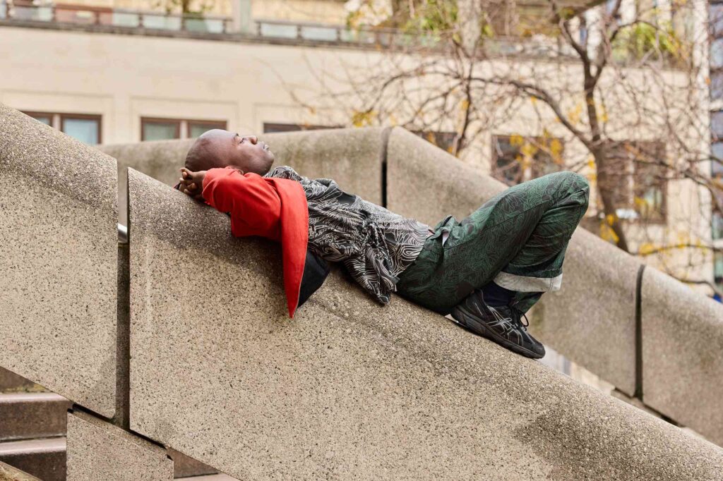 Folu Odimayo reclining on a brutalist architecture handrail in London, UK