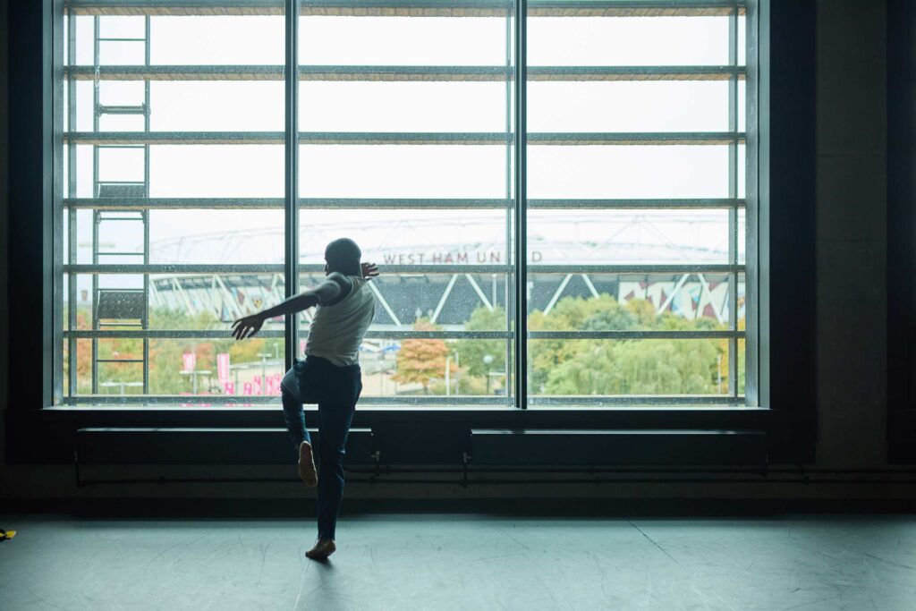 Folu Odimayo dances in front of a large window on a grey day in London, UK