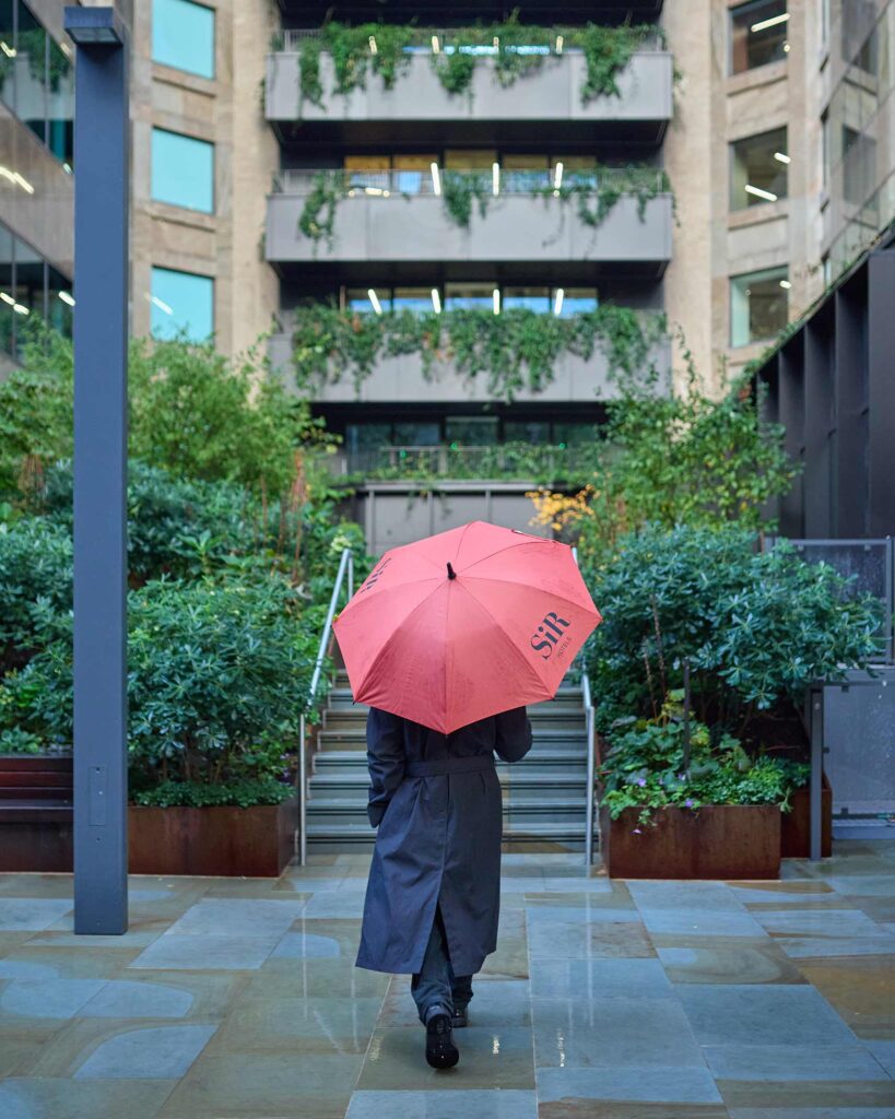 Model with a red umbrella is photographed from behind in London, UK