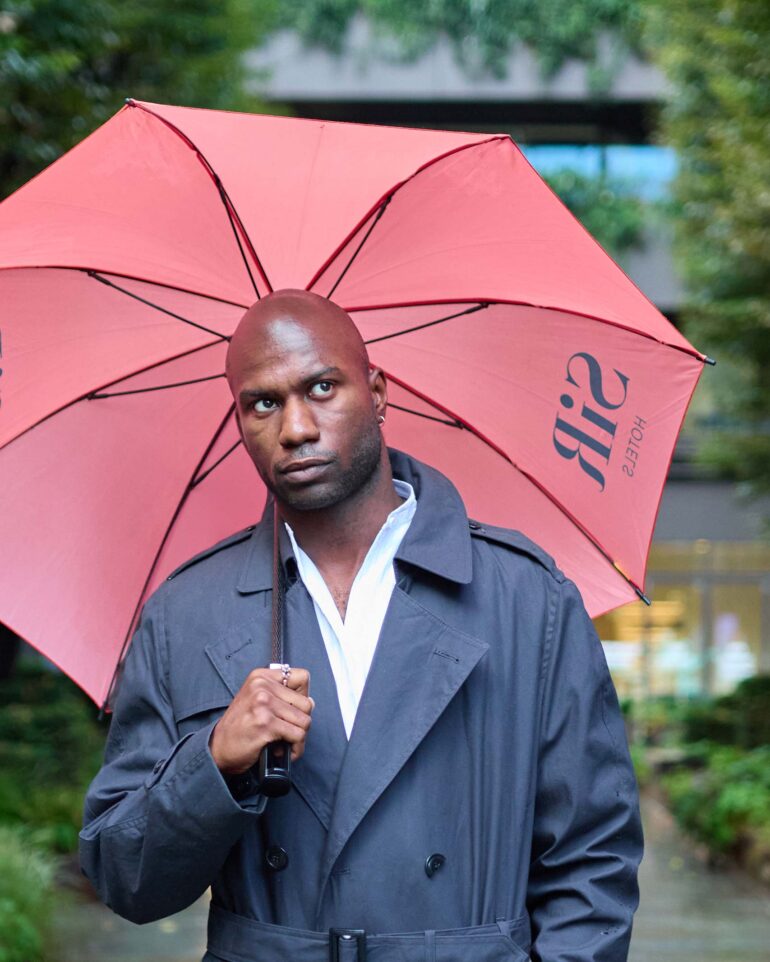 Folu Odimayo with a red umbrella by Sir Hotels in London, UK